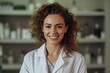 Portrait of smiling young female cosmetologist in white coat looking at camera