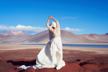 Conceptual Artistic Beauty Portrait Woman With Long Dress And Face Covered With Cloth On Red Stones In The Altiplano