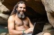 Ancient human using a laptop in a cave, showcasing the advancement of human progress. Time, Knowledge, Technology concept created with generative AI.