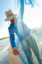 A woman wearing a sun hat sorts out a fishing net along the Mississippi River near Clarksdale, Mississippi