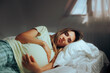 Pregnant Woman Sleeping in her Bedroom Resting in Bed. Mother to be relaxing and taking a nap at home
