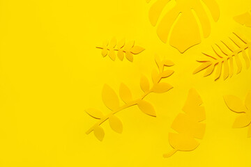 Different paper tropical leaves on yellow background