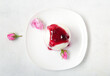 Plate of panna cotta with berry sauce and beautiful pink rose flowers on white table