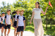 © Blue Jean Images - Cheerful school children walking in park with their teacher