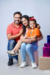 Wall Mural - Indian happy family of a father, mother and daughter sitting together on a white background.