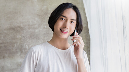 Portrait of young handsome asian man hand on smartphone and coffee mug in bedroom. Smile happy asian boy in bed morning lifestyle near window. Japanese man with technology, modern minimal concept