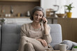 © fizkes - Cheerful pretty grey haired woman talking on mobile phone at home, enjoying conversation, enjoying wireless connection, positive telephone conversation, smiling, laughing