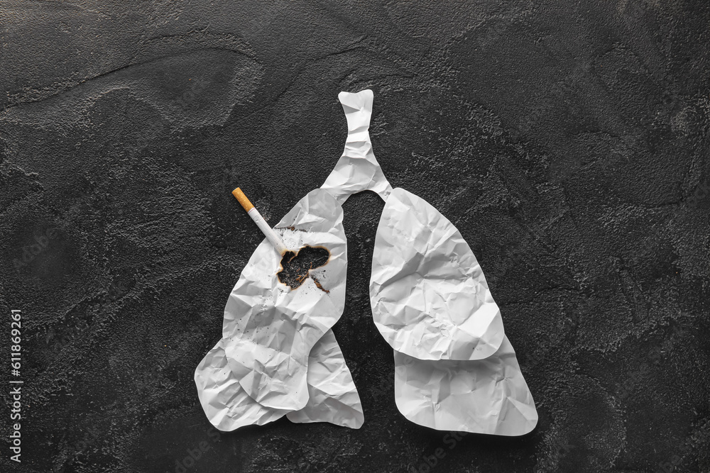 Burned paper lungs with cigarette on dark background. Stop smoking concept