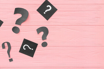 Paper question marks on pink wooden background