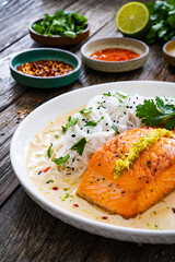 Wall Mural - Creamy coconut lime salmon with rice noodles on wooden table