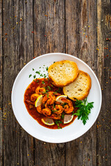 Wall Mural - Louisiana style shrimp in hot sauce with bread on wooden table