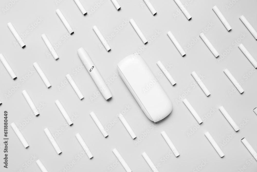 Modern electronic cigar and many sticks on grey background