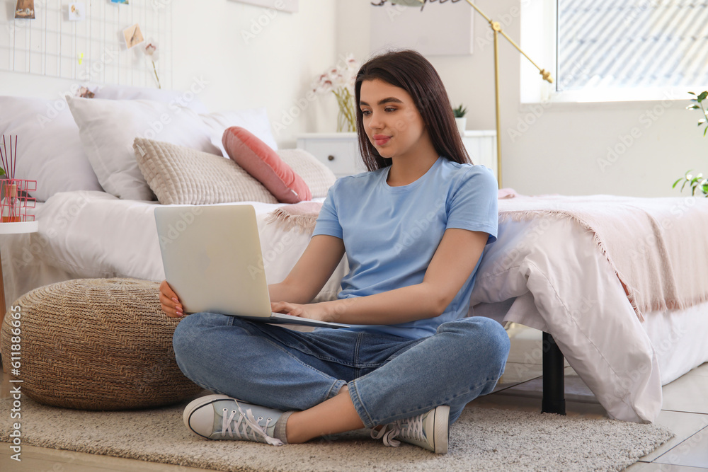 Female freelancer working with laptop in bedroom
