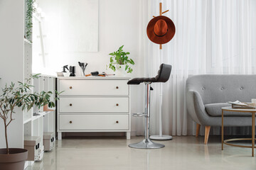 Sticker - Stylish chest of drawers with hairdressing tools and chair in beauty salon