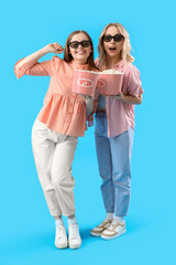 Poster - Young sisters in 3D glasses with popcorn on blue background