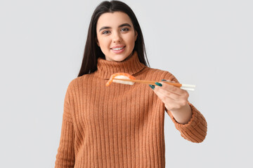 Canvas Print - Young woman with sushi on light background