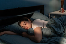 Young Female Sleeping Peacefully In Her Bedroom At Night. Relaxing At Nighttime