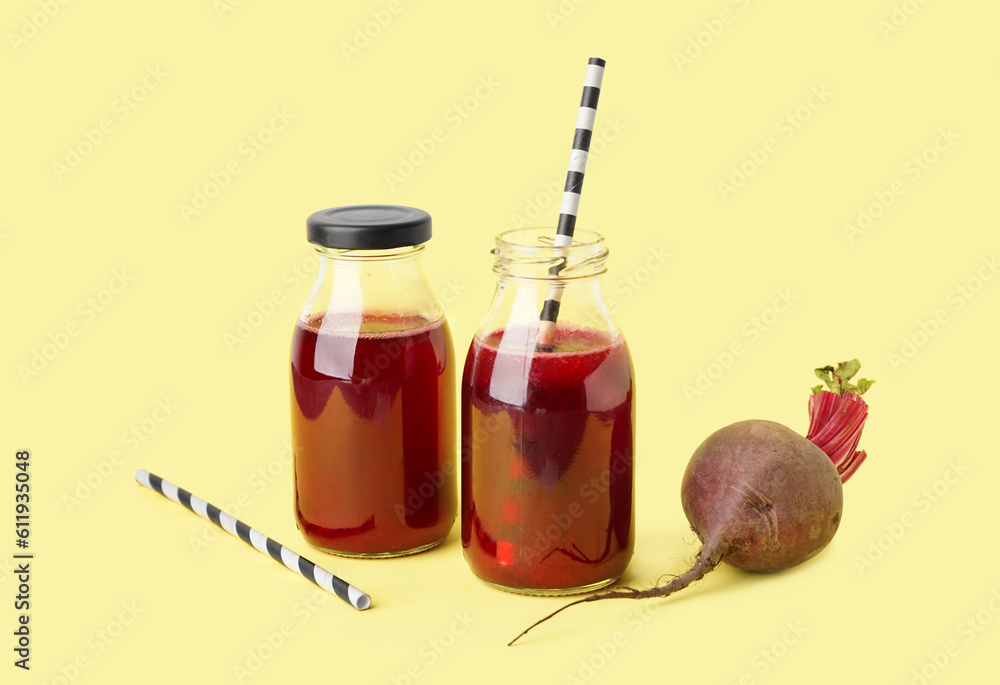 Bottles of healthy beet juice on yellow background