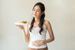 © KMPZZZ - Gluten allergy, asian young woman hand holding, refusing to eat, looking at bread slice on plate in breakfast food meal at home, having a stomach ache. Gluten intolerant and Gluten free diet concept.