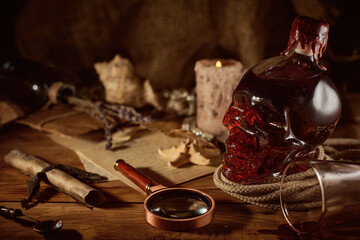 Vintage pirate still life with candle, compass, dark rum in a skull bottle and old papers