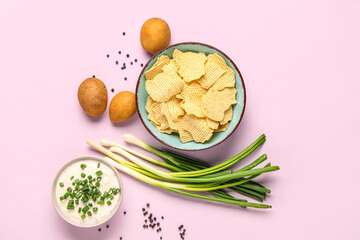 Bowl of tasty sour cream with sliced green onion and potato chips on lilac background