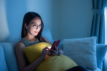 Wall Mural - Woman with glasses and use of smart phone at home in the evening