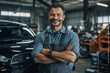 portrait of smiling mechanic with crossed arms standing with crossed arms in auto repair shop