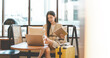 © dodotone - Business asian entrepreneur woman sitting in lounge with laptop and travel luggage