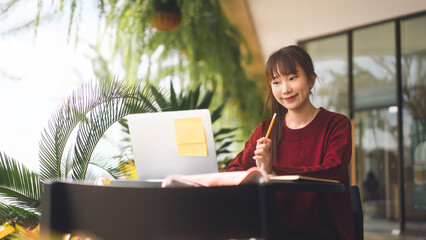 Wall Mural - Young adult asian student woman using laptop at cafe for study and work or business