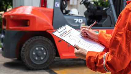 Wall Mural - a mechanical engineer is using heavy equipment checklist form for inspecting the factory forklift ve