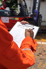 Wall Mural - a mechanical engineer is using heavy equipment checklist form for inspecting the factory forklift ve