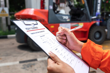 Wall Mural - a mechanical engineer is using heavy equipment checklist form for inspecting the factory forklift ve