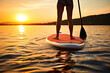 Woman standing on SUP standup paddle board paddling into sunset. Generative AI.