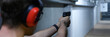 Male shooter in headphones aiming pistol at target in shooting range