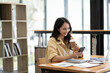 © PaeGAG - Asian businesswoman playing with mobile phone inside modern office