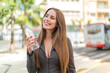 © luismolinero - Young woman with a bottle of water at outdoors looking up while smiling