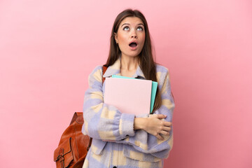 Wall Mural - Young student woman isolated on pink background looking up and with surprised expression