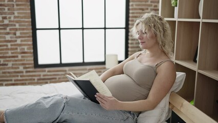 Poster - Young pregnant woman reading book touching belly at bedroom