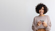 Photo of cheerful delighted woman types sms on modern cell phone device, enjoys good internet connection, using social media, isolated on grey studio wall, smiling, with copy space