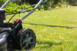 Lawn mower cutting grass in the garden. Gardening.