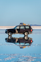 Wall Mural - a 4x4 in a salt flat with water that generates a perfect reflection