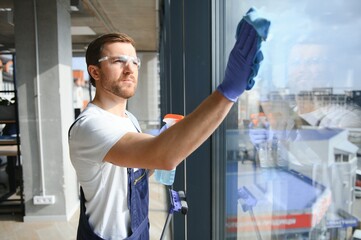 An employee of a professional cleaning service washes the glass of the windows of the building. Showcase cleaning for shops and businesses.