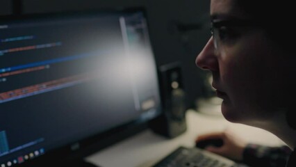 Programmer specialist in programming works remotely at home uses a laptop computer. Computer monitor in a dark room freelancer working from home at night. Remote work in a European apartment
