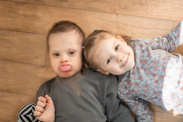 Wall Mural - Boy plays with his younger sister on the bed in home bedroom. Down syndrome and ASD