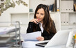© JackF - Portrait of cheerful woman office worker sitting at table and doing her daily paperwork.