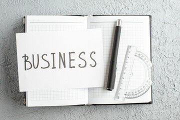 Wall Mural - close up view of business writing on white sheet pen ruler on new open notebook on gray sand backgro