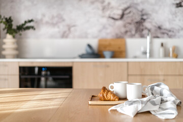 Wall Mural - wooden table with mugs of tea and fresh pastry in modern kitchen