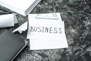 Wall Mural - front view of white sheet with business writing and notebook ruler pens blanks paper plane on gray d