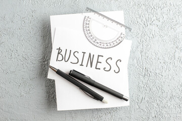 Wall Mural - top view of business writing on white sheet ruler pens on gray sand background with free space