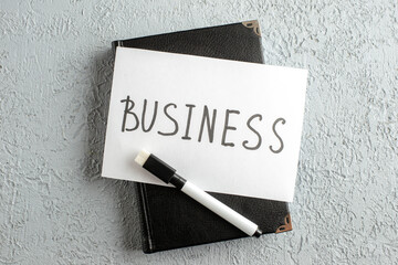 Wall Mural - top view of business writing on white sheet and marker on new black closed notebook on gray sand bac